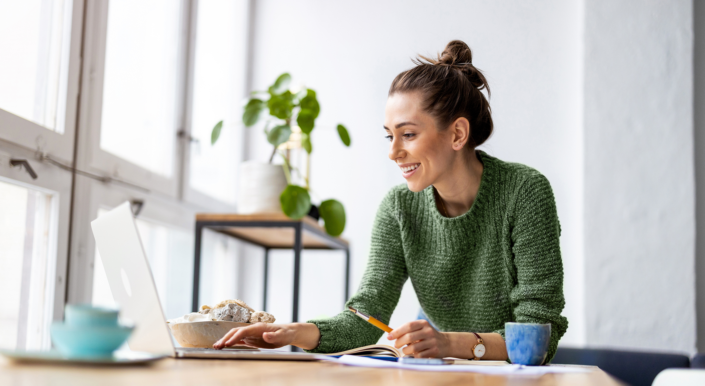 Woman working on a laptop at a bright kitchen table